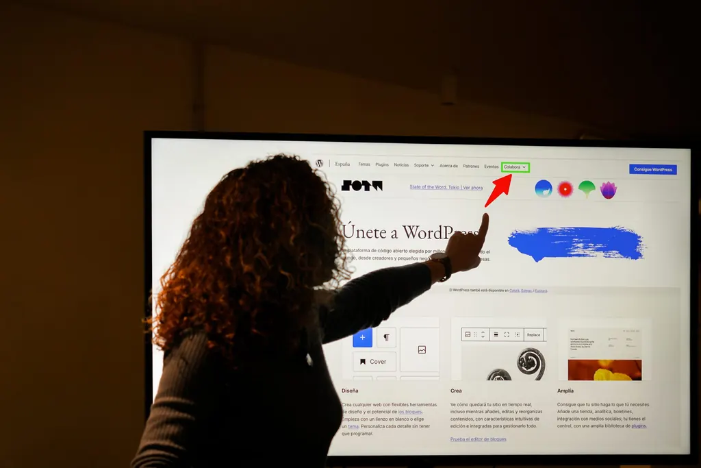 Person silhouetted against a large screen, pointing at a highlighted item in a website navigation menu