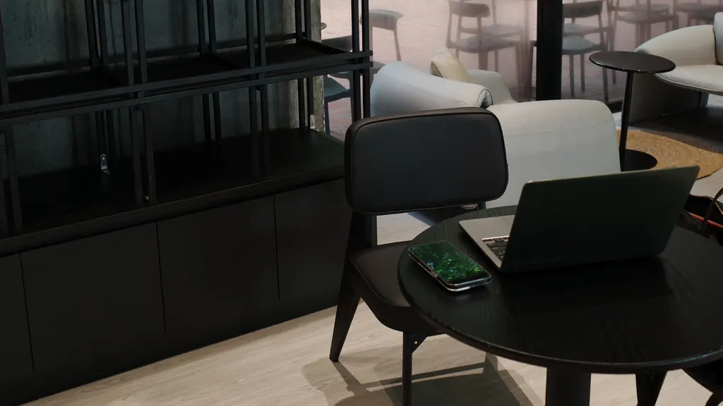 Open laptop and a smartphone on a round black table in a quiet, minimalist workspace