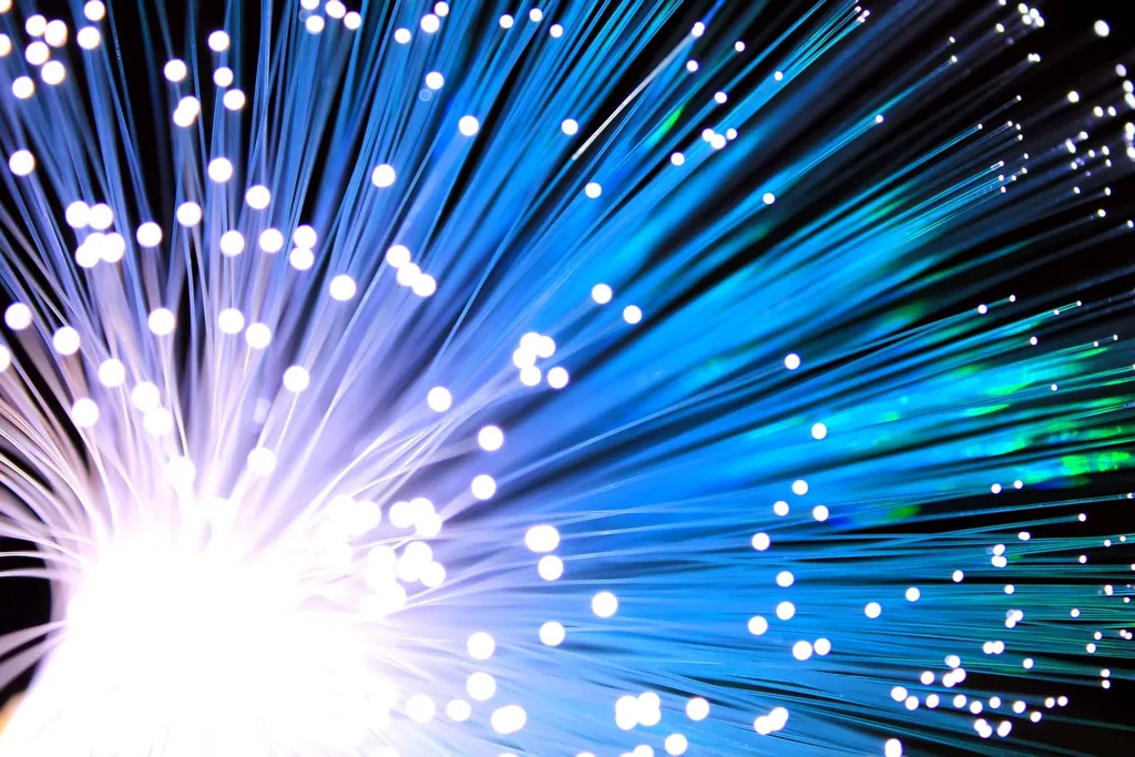 Glowing strands of fibre-optic cable fanning out against a dark background