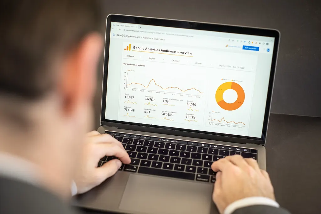 A person typing on a laptop showing a website analytics dashboard with traffic charts